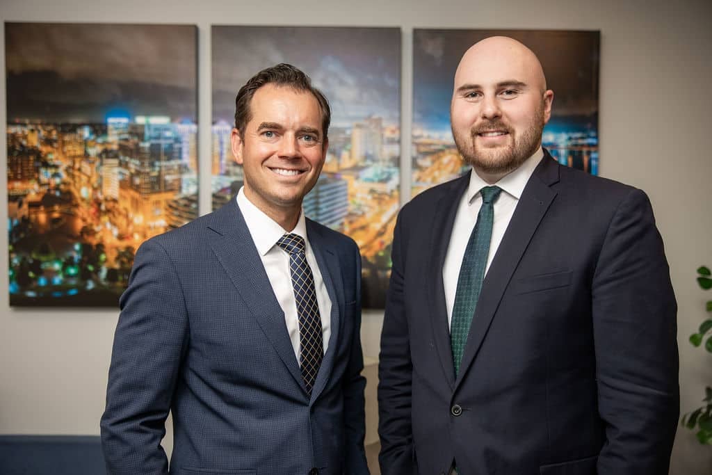 Two Med Contract Law attorneys in front of city skyline artwork